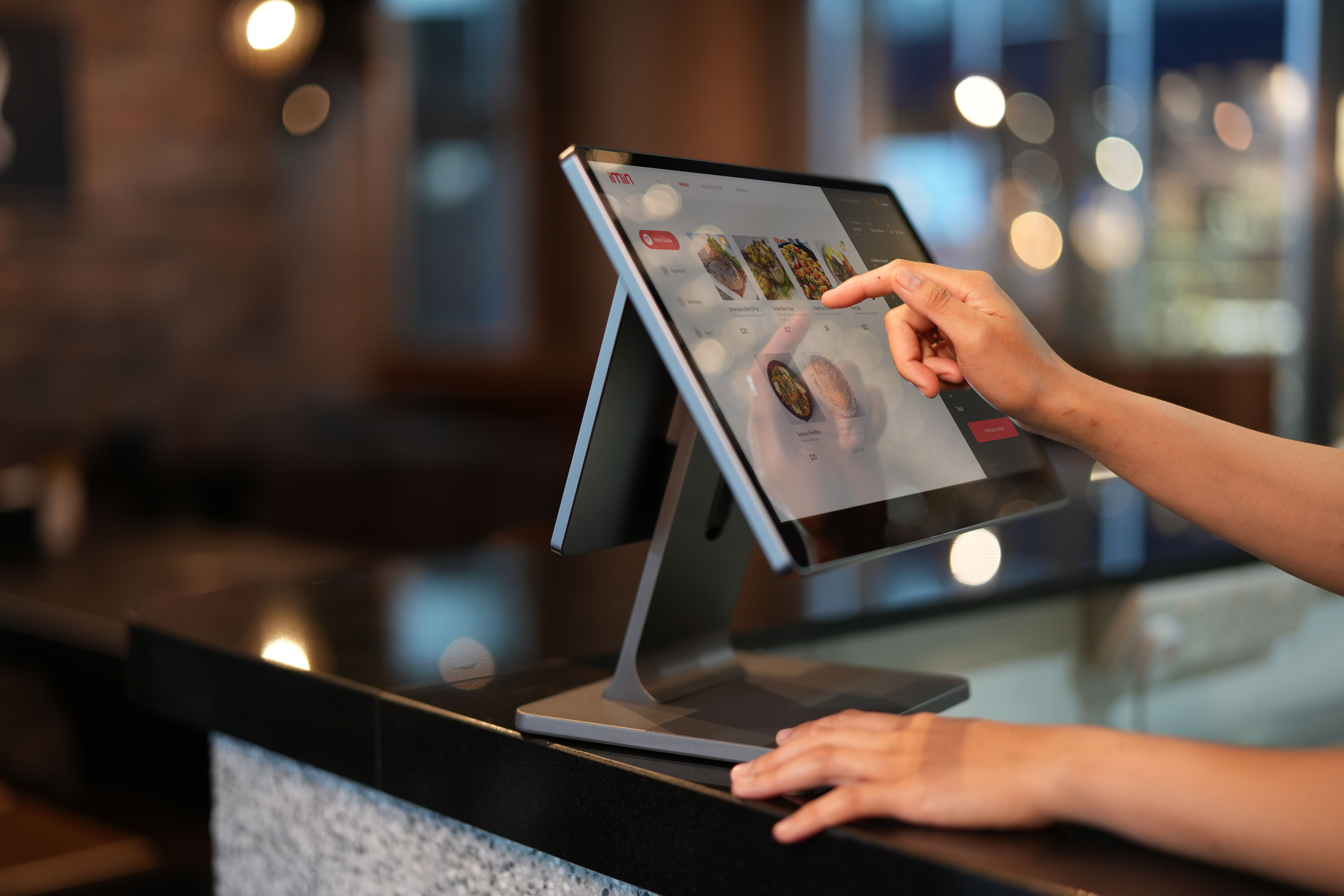 Une vendeuse derrière un comptoir tenant un terminal de paiement